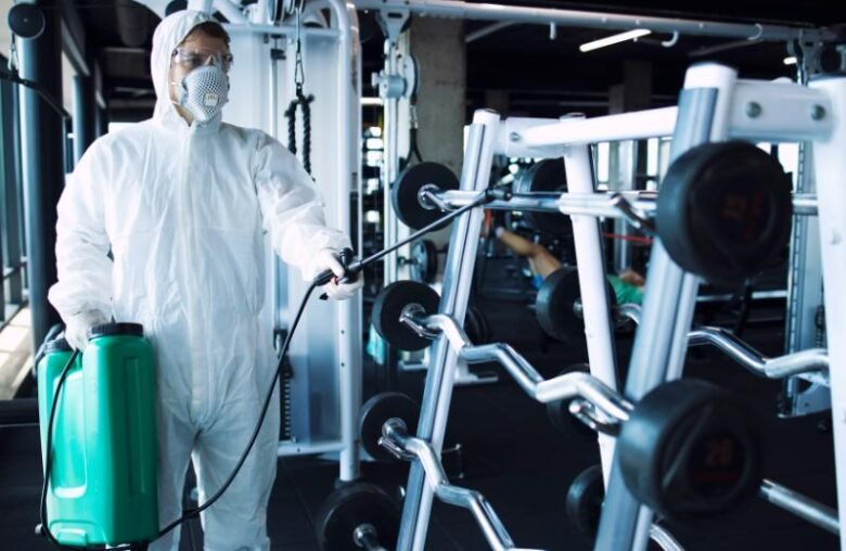 man-white-protection-suit-disinfecting-fitness-equipment-weights-stop-spreading-highly-contagious-corona-virus (1)