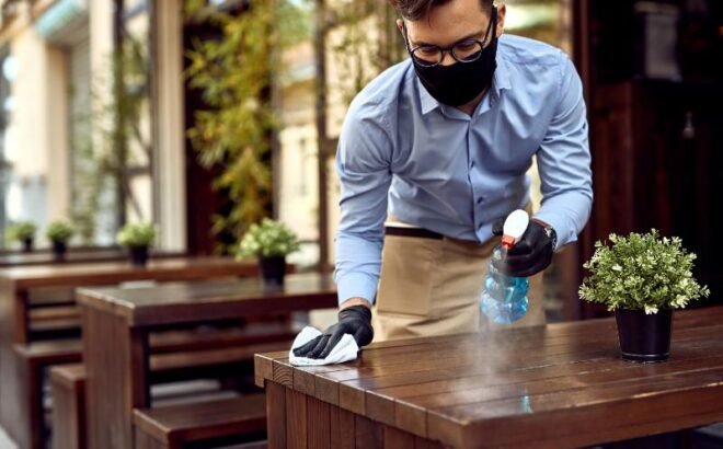 waiter-wearing-protective-face-mask-while-disinfecting-tables-outdoor-cafe (1)