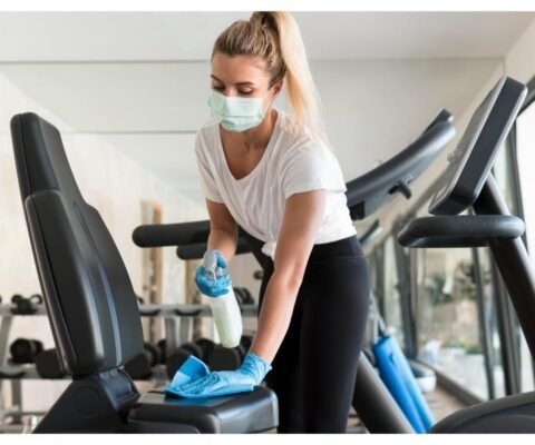 woman-with-medical-mask-cleaning-gym-equipment (1)